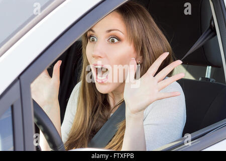 Jeune femme pilote voiture effrayés à l'avance en ligne droite. Choqué belle fille dans une voiture Banque D'Images