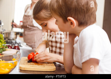 Arrière-plan de cuisine familiale. Soeur et frère de tomate et mère de coupe n'y avoir dans la cuisine Banque D'Images