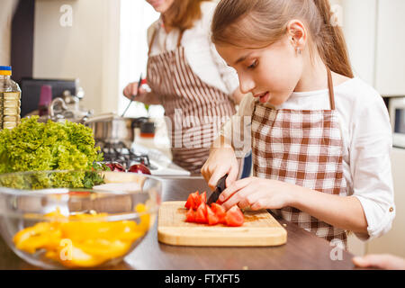 Petite adolescente tomates coupe en salade. Arrière-plan de cuisine familiale Banque D'Images