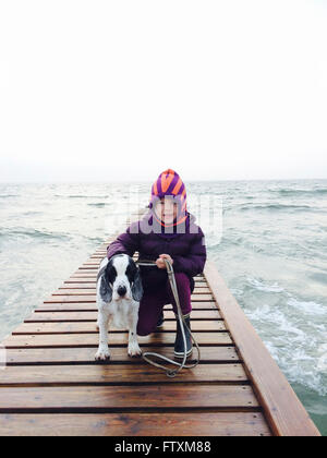 Fille et son chien sur la jetée par la mer Banque D'Images