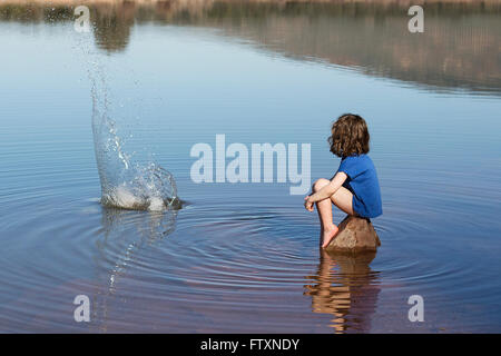 Fille assise sur un rocher dans le lac pierre pierres Banque D'Images