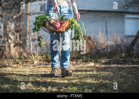 Woman carrying basket of fresh vegetables Banque D'Images