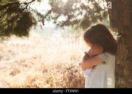 Vue latérale d'une fille en pleine campagne hugging une poupée, Grenade, Andalousie, Espagne Banque D'Images