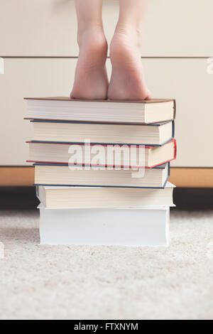 Fille debout sur une pile de livres Banque D'Images