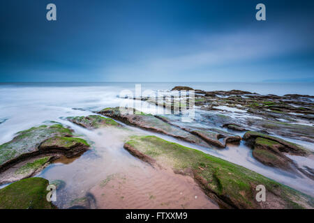La formation de Red Rock Beach à Exmouth dans le Devon, Royaume-Uni. Une longue exposition blured l'eau de mer. Banque D'Images