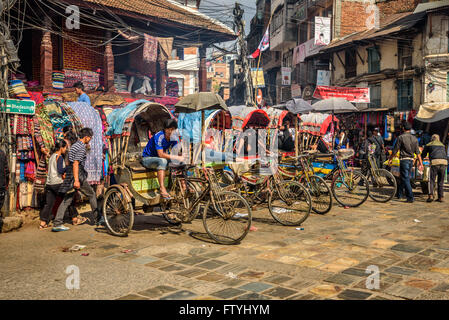 Pousse-pousse traditionnelle népalaise garée dans la rue avec des pilotes en attente de clients. Banque D'Images