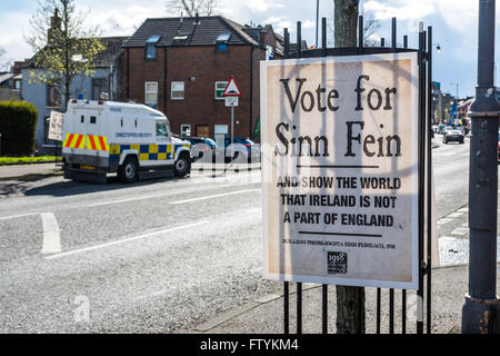 Voter pour le Sinn Fein affiche électorale sur Belfast's Falls Road avec land rover PSNI garé en arrière-plan. Banque D'Images