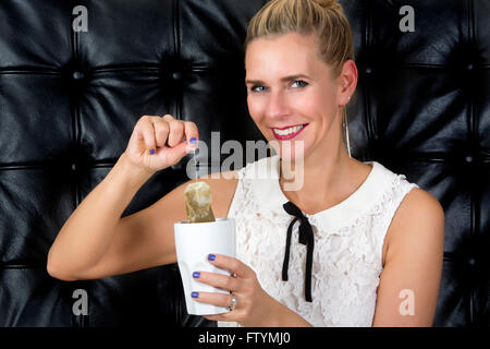 Blonde femme à boire le thé en face de fond en cuir noir Banque D'Images