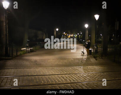 Street musician playing accordion sur une sombre nuit de tempête, venteux et dans les ruelles du vieux quartier de Cracovie, Pologne Petite Banque D'Images