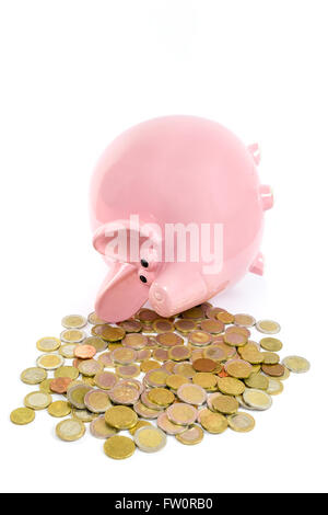 Lying pink piggy bank with pile de pièces en euros isolé sur fond blanc Banque D'Images