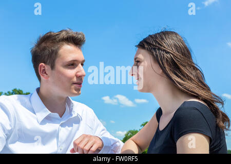 Jeune homme et femme en aime parler dehors avec ciel bleu Banque D'Images