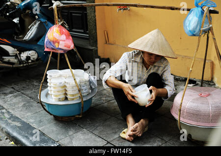 Jeune femme vietnamienne avec chapeau conique vendent des produits alimentaires typiques de la vieille ville de Hanoi, Vietnam Banque D'Images