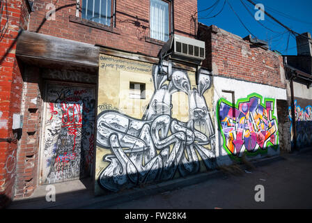 Un mur couvert de graffitis et porte sur un immeuble dans une ruelle de Kensington Market, à Toronto (Ontario) Canada. Banque D'Images