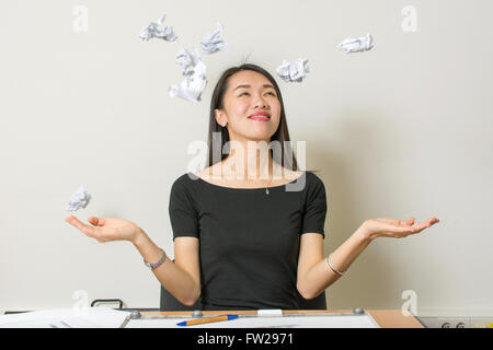 Happy asian woman throwing crumpled papers au travail Banque D'Images