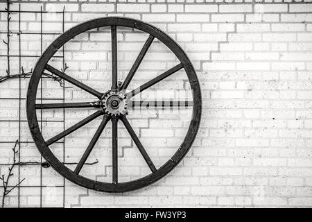 Vieille roue pendante sur un mur en noir et blanc Banque D'Images