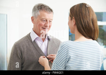 Aider sa fille adulte Senior Man à Cardigan Bouton Banque D'Images