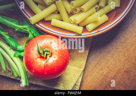 La tomate fraîche à côté assiette pleine de matières les macaronis. Top View with copy space Banque D'Images