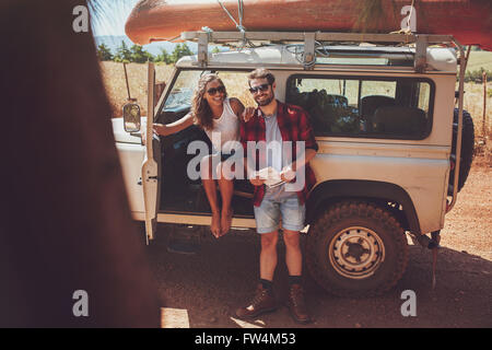 Portrait of happy young couple en faisant une pause sur roadtrip. Jeune homme et femme bénéficiant d'un voyage en vacances. Banque D'Images