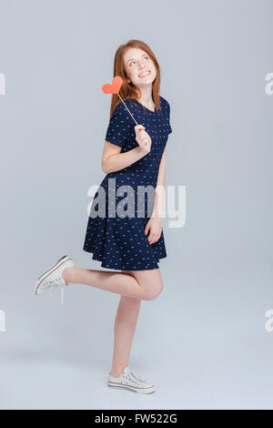 Portrait of a happy woman holding red Heart plus de gray backgorund Banque D'Images