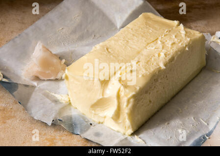Close up sur un grand pat de beurre de ferme avec l'enveloppe ouverte sur une table en bois dans une boulangerie pour utilisation comme ingrédient de cuisson Banque D'Images