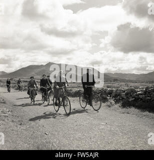 Années 1950, photo historique par J Allan Cash de certains habitants de la région à vélo de l'époque, à vélo le long d'une ruelle rurale dans l'ouest de l'Irlande, peut-être va travailler sur les fermes et les villages. Banque D'Images