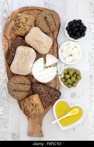 Les petits pains avec le camembert et le fromage feta sur une carte en bois d'olivier avec olives vertes et noires. Banque D'Images