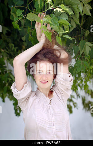 Jeune femme dans le parc. L'inspiration. La respiration, la relaxation, l'atmosphère. L'humeur de l'été. Portrait d'une fille dans les feuilles de cheveux smiling Banque D'Images