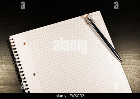 Ordinateur portable ouvert avec des pages vierges et un crayon noir sur fond de bois Banque D'Images