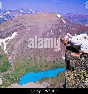 Self Portrait de John l'agnelage prudemment sur le rebord de peering du mont siyeh headwall 4 000 pieds au-dessus du lac cracker dans le Glacier National Park, Montana Banque D'Images