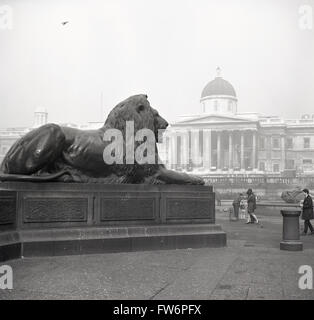 Historique des années 1950, l'une des statues de lion en bronze des gardes que "la Colonne Nelson à Trafalgar Square, Londres, Angleterre. Banque D'Images