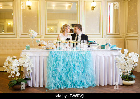 Wedding couple assis à la table sur un banquet Banque D'Images