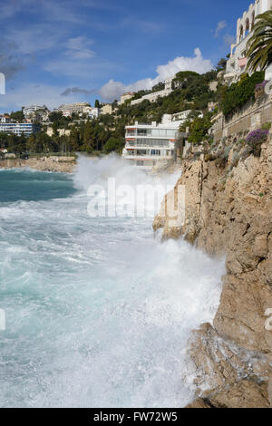 L'hiver, les vagues se brisent sur une falaise de calcaire et tout à fait près d'un immeuble d'appartements.Nice, Alpes-Maritimes, Côte d'Azur, France. Banque D'Images