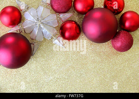 Ampoule de Noël rouge et décorations en forme d'une frontière de cime au sommet d'un background gold glitter tissu avec copie-espace. Banque D'Images