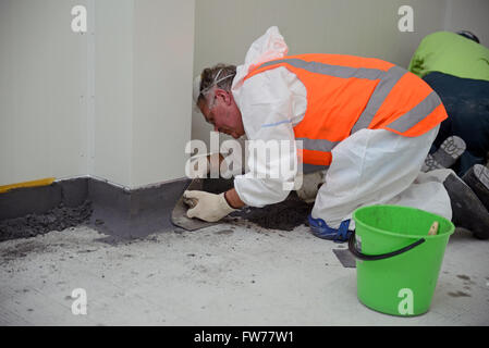 Un commerçant s'accumule sur le produit époxy voussures le long du bord d'un plancher dans un bâtiment industriel Banque D'Images