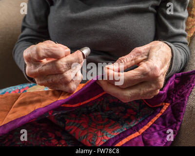 Photographie de la mains d'une femme de la haute couture la liaison sur un patchwork coloré. Banque D'Images