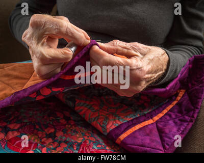 Photographie de la mains d'une femme de la haute couture la liaison sur un patchwork coloré. Banque D'Images