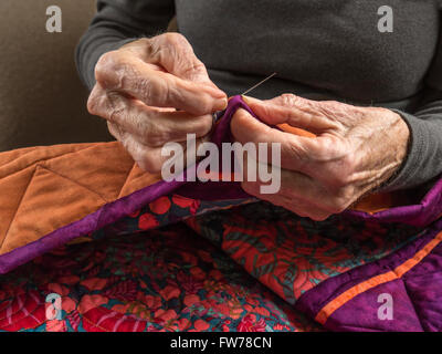 Photographie de la mains d'une femme de la haute couture la liaison sur un patchwork coloré. Banque D'Images