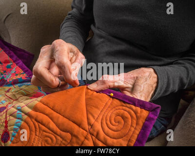 Photographie de la mains d'une femme de la haute couture la liaison sur un patchwork coloré. Banque D'Images