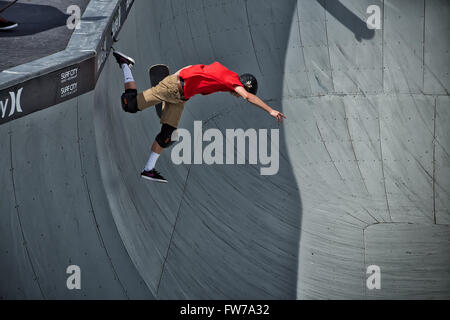 Un skateboarder professionnel tombe à travers l'air du haut de la cuvette dans un tournoi. Banque D'Images
