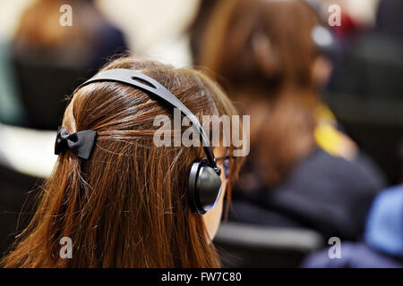 À l'aide de personnes méconnaissables dans l'oreille d'écouteurs pour la traduction pendant l'événement Banque D'Images