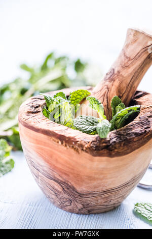 Menthe fraîche herb dans mortier rustique en bois sur table en bois Banque D'Images