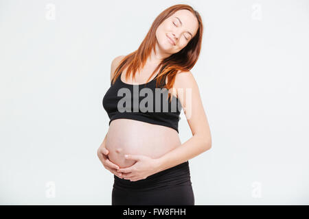 Femme enceinte détendue debout isolé sur fond blanc Banque D'Images