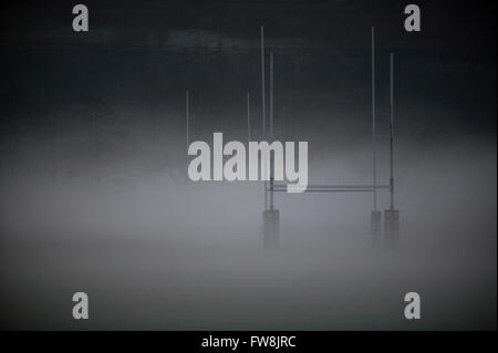 Rugby posts apparaissant hors d'un matin tôt de brume à un terrain d'entraînement au Royaume-Uni. Le terrain vide apparaît à travers le brouillard dans une errie à paysage. Banque D'Images