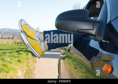 Femme jambes hors de la fenêtre de voiture. Billet et fun Banque D'Images