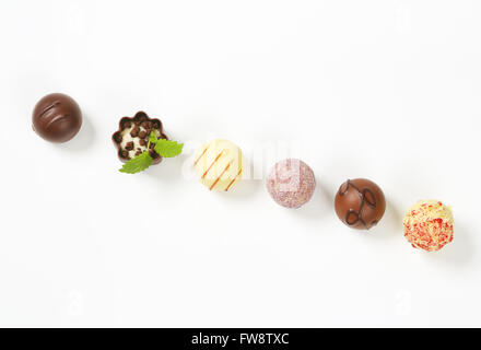 Ligne d'un assortiment de pralines en chocolat belge sur fond blanc Banque D'Images