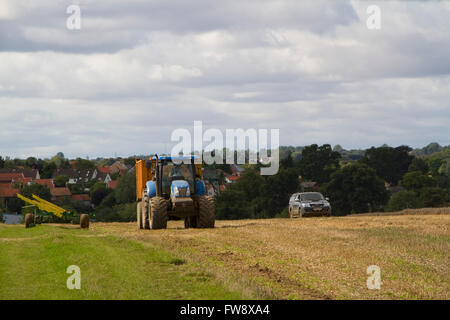 Un tracteur avec remorque et un véhicule traversant un champ fraîchement récoltés Suffolk Banque D'Images