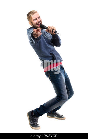 Studio portrait d'un homme chantant avec microphone isolé sur fond blanc, un beau jeune homme aux cheveux blonds le chant avec dri Banque D'Images