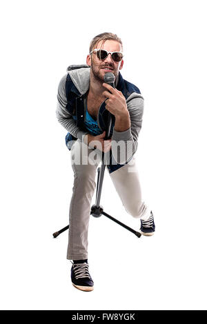 Studio portrait d'un homme chantant avec microphone isolé sur fond blanc, un beau jeune homme aux cheveux blonds le chant avec dri Banque D'Images