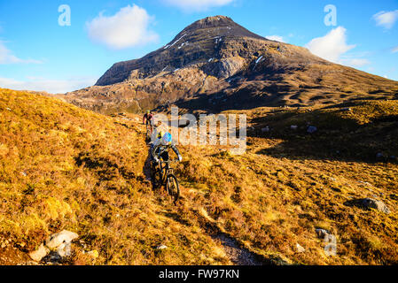 Les vététistes sur la descente de Bealach na pou du poisson en Ecosse Highland Torridon avec Maol Chean-dearg derrière Banque D'Images