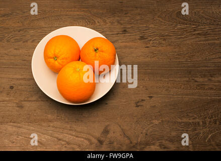 Trois oranges dans un bol en porcelaine blanche Banque D'Images